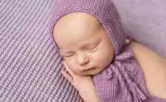 可爱的女孩紫色的针织阀盖睡觉一边