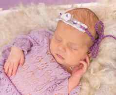 甜蜜的新生儿睡觉广场床紫罗兰色的背景