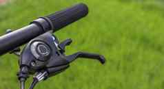 山自行车操舵轮绿色草背景细节体育事件关闭黑色的山自行车旋钮变速器旋钮左移动装置