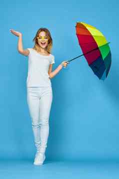 时尚女人伞彩虹颜色摆姿势蓝色的背景