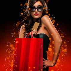 圣诞节黑色的星期五出售概念购物女人持有红色的袋孤立的黑暗背景假期