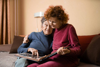 积极的岁的女士们专辑照片坐着沙发首页快乐的朋友高级女人成熟的护士看照片专辑奶奶显示女儿记忆过去的