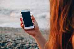 认不出来年轻的女人持有移动电话海滩波海日落社会媒体现代技术夏季假期