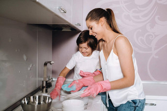 家庭主妇妈妈粉红色的手套洗菜儿子手水槽洗涤剂女孩白色孩子投清洗房子洗菜自制的粉红色的手套孩子投洗菜微笑