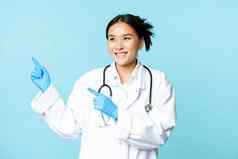 亚洲微笑医生医疗医疗保健工人指出手指左很高兴广告广告产品蓝色的背景