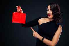 黑色的星期五出售概念商店购物女人持有红色的袋孤立的黑暗背景