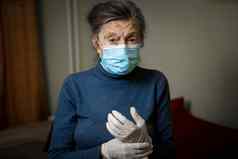 高加索人女人穿着个人保护设备面具手套鼓励保持首页疫情安全健康护理上了年纪的护理主题