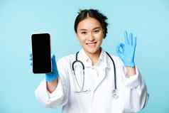 网络医疗保健在线概念自信亚洲女医生护士显示智能手机屏幕应用程序接口标志批准推荐网站