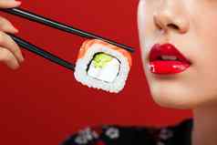 特写镜头肖像亚洲女人寿司吃寿司卷红色的背景黑色的星期五寿司出售