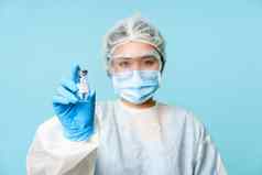 科维德疫苗接种概念亚洲女护士医生个人保护设备显示冠状病毒疫苗瓶站蓝色的背景