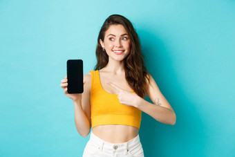 肖像可爱的浅黑肤色的女人女人指出手指智能手机屏幕左复制空间站夏天装蓝色的背景