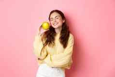 医疗保健口腔学人概念快乐女孩显示白色完美的牙齿微笑绿色苹果吃健康的食物水果站粉红色的背景