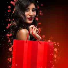 圣诞节黑色的星期五出售概念购物女人持有红色的袋孤立的黑暗背景假期