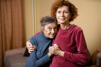 上了年纪的可爱的女人<strong>老年痴呆</strong>症快乐微笑老大女儿拥抱需要护理首页沙发主题老化育儿家庭的关系社会护理最古老的