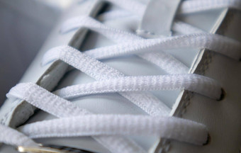 白色运动系带的运动鞋白色鞋带系特写镜头模糊背景体育概念金属铆钉鞋子细节元素时尚时尚的鞋子