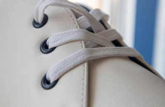白色皮革运动鞋系带的鞋子白色鞋带系特写镜头模糊背景体育概念金属铆钉鞋子细节元素时尚时尚的鞋子