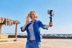 中间岁的女人记录视频智能手机海假期自然海景背景