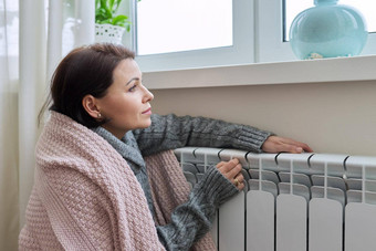 冬天加热季节女人温暖的毛衣坐着首页房间加热散热器
