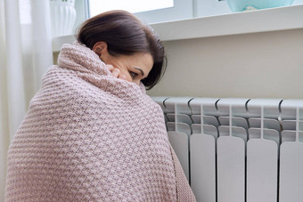 冬天加热季节女人温暖的毛衣坐着首页房间加热散热器