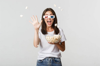 快乐的有吸引力的年轻的女孩眼镜扔爆米花屏幕看电影