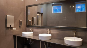 铬水龙头白色轮洗手盆公共厕所。。。大镜子灰色的墙现代室内公共厕所。。。