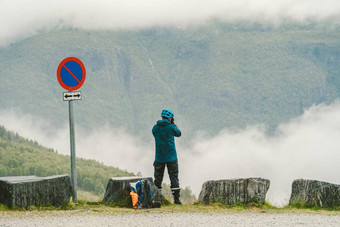 男人。头盔摄影师采取照片回来视图山景观多雨的天气挪威旅行生活方式旅游热冒险概念假期户外野生