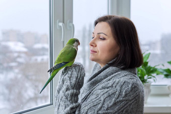 中间岁的女人鹦鹉女鸟老板会说话的绿色贵格会教徒宠物