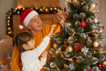 家庭装修圣诞节树首页祖父支出时间女儿一年夏娃高级男人。穿圣诞老人老人他黄色的衬衫孩子辫子白色跳投