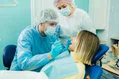 牙医保护面具坐在对待病人牙科办公室助理