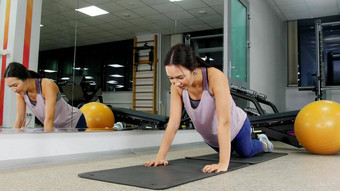 培训年轻的女人健身房推联合包裹地板上