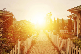 人行道上别墅花园不断上升的太阳