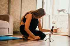年轻的女人长头发健身教练黑色的运动服装伸展运动普拉提瑜伽席首页女健身瑜伽例程概念健康的生活方式和谐冥想