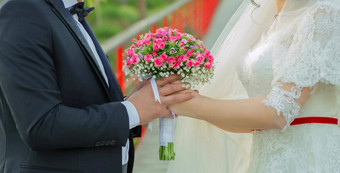 举行粉红色的花花束手手折叠回来持有美丽的婚礼花束玫瑰新婚夫妇持有手婚礼花束