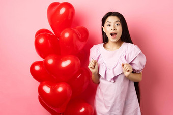 兴奋惊讶十几岁的朝鲜文女孩开放口惊讶收到惊喜礼物情人节一天想知道站<strong>心气球</strong>粉红色的背景