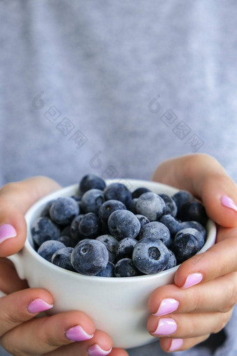 女人持有碗冻蓝莓水果收获概念女手收集浆果健康的吃概念长袜浆果冬天素食者素食主义者食物