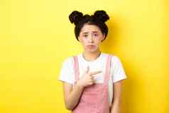 伤心失望亚洲女孩皱着眉头感觉不公平的指出手指坏事情抱怨令人心烦意乱的黄色的背景