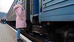 女人灰色的针织他粉红色的夹克皮毛进入马车火车站铁路运输秋天冬天旅行概念铁路运输