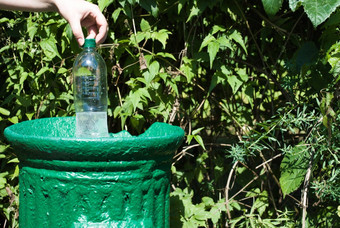 女手抛出塑料瓶小铁垃圾绿色公园夏天关闭自然保护塑料