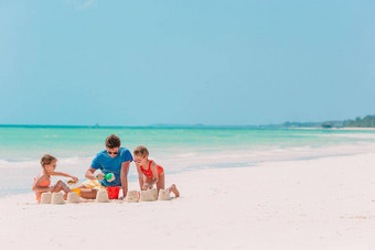父亲孩子们使<strong>沙子城堡</strong>热带海滩家庭玩海滩玩具