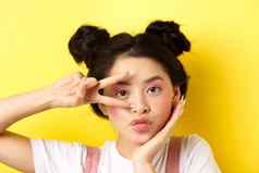 特写镜头可爱的亚洲女人明亮的魅力化妆长指甲显示地摆撅嘴愚蠢的相机站卡哇伊黄色的背景