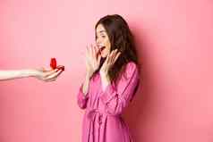 肖像惊讶女朋友收到婚姻建议手订婚环尖叫惊喜兴奋站粉红色的背景