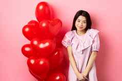 可爱的亚洲女孩衣服害羞的微笑站适度的情人节一天气球脸红浪漫的日期相机粉红色的背景