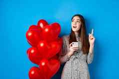 情人节一天图像浪漫的女孩投手的想法移动电话提高手指空空间站红色的心气球蓝色的背景
