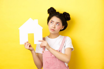 真正的房地产家庭概念深思熟虑的亚洲女孩梦想房子显示纸首页断路上左角落里沉思的黄色的背景