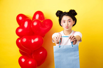快乐情人节一天可爱的亚洲女朋友给情人礼物拉伸手购物袋愚蠢的站黄色的背景心气球