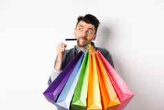 梦幻的家伙思考购物持有色彩斑斓的袋购买项目站深思熟虑的信贷卡白色背景