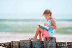 可爱的女孩阅读书热带白色海滩
