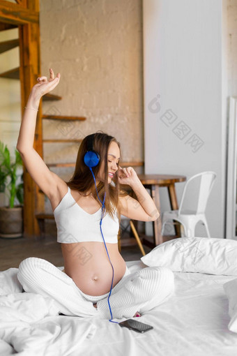 怀孕了女人坐在床上首页享受<strong>舒缓</strong>的<strong>音乐</strong>听<strong>音乐</strong>在线智能手机应用程序