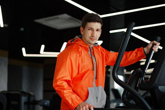 肖像年轻的男人。橙色<strong>风衣</strong>锻炼健身机健身房