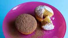 凝乳蛋糕撒巧克力糖衣糖粉红色的板蓝色的背景甜点小蛋糕白色烤饼干艾里纹理食物概念